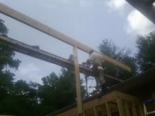 Carpenter setting a ridge beam over a new addition frame — Ice Dam Removal by Roofing Brothers in Callender