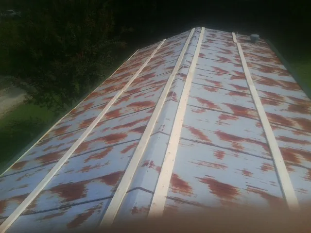 Rusted metal roof panels with new wood purlins before replacement — Storm Damage Roof Repair in Callender by Roofing Brothers