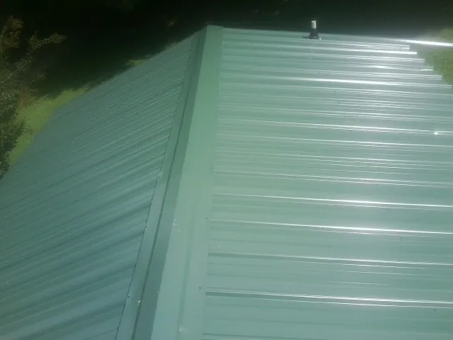 New green metal panels meeting at the ridge of a roof — Flat Roof Repair work by our crew in Callender
