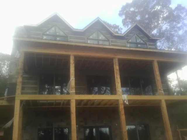 Dormers and porch framing on a large log home under construction — Roof Coating work by our crew in Callender