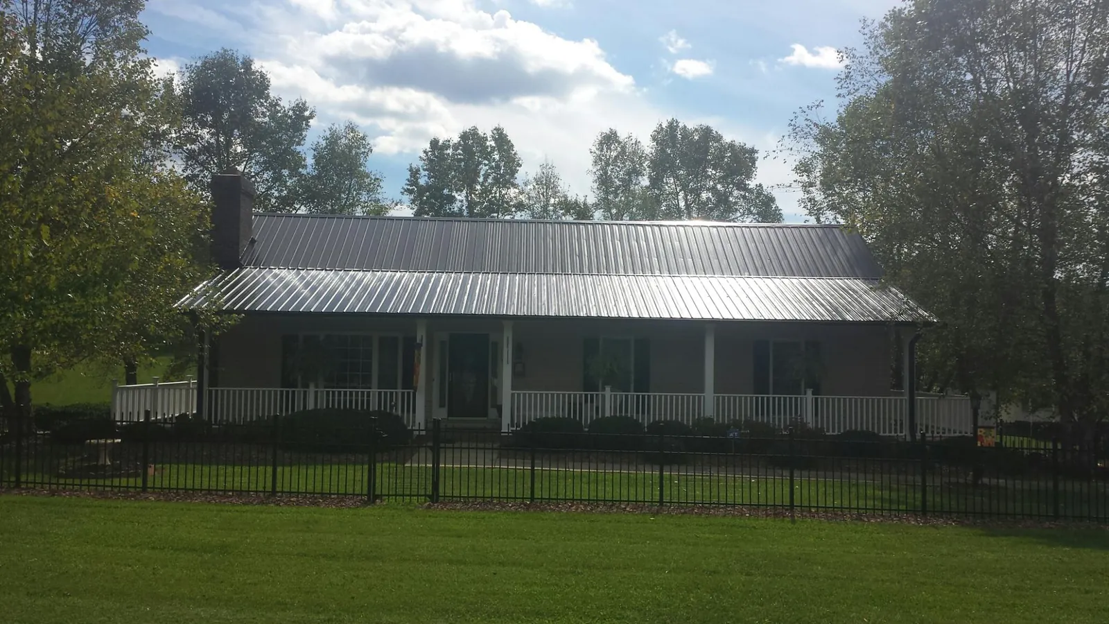 Gray metal roof on a brick ranch with a full width front porch — Gutter Guard Installation work by our crew in Callender