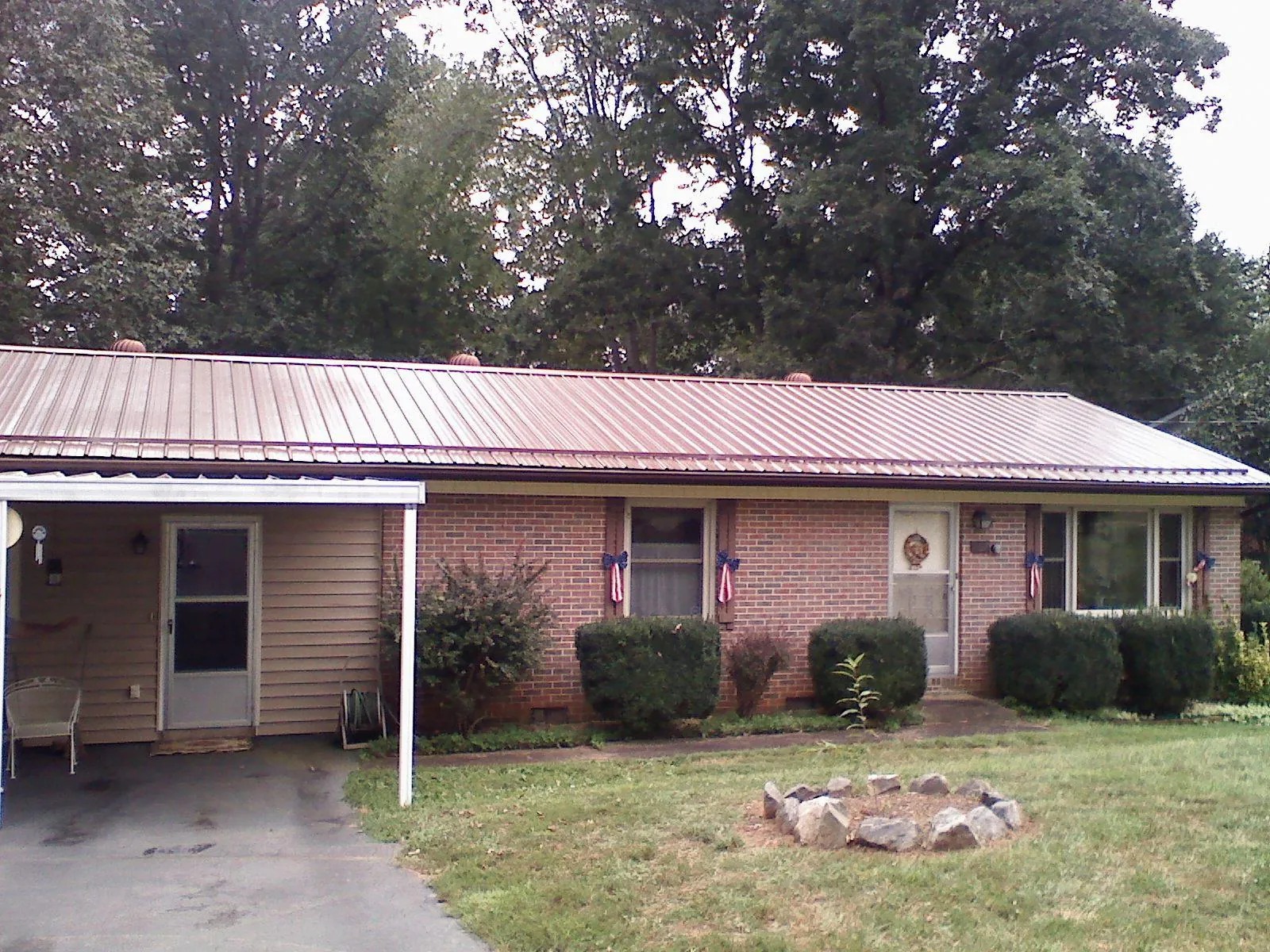 Bronze metal roof and carport on a brick ranch home — Roof Repair work by our crew in Callender