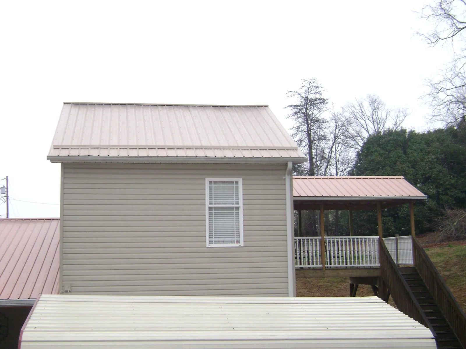 Tan metal roofs on a two story addition and attached porch, from a Roof Replacement job in Callender