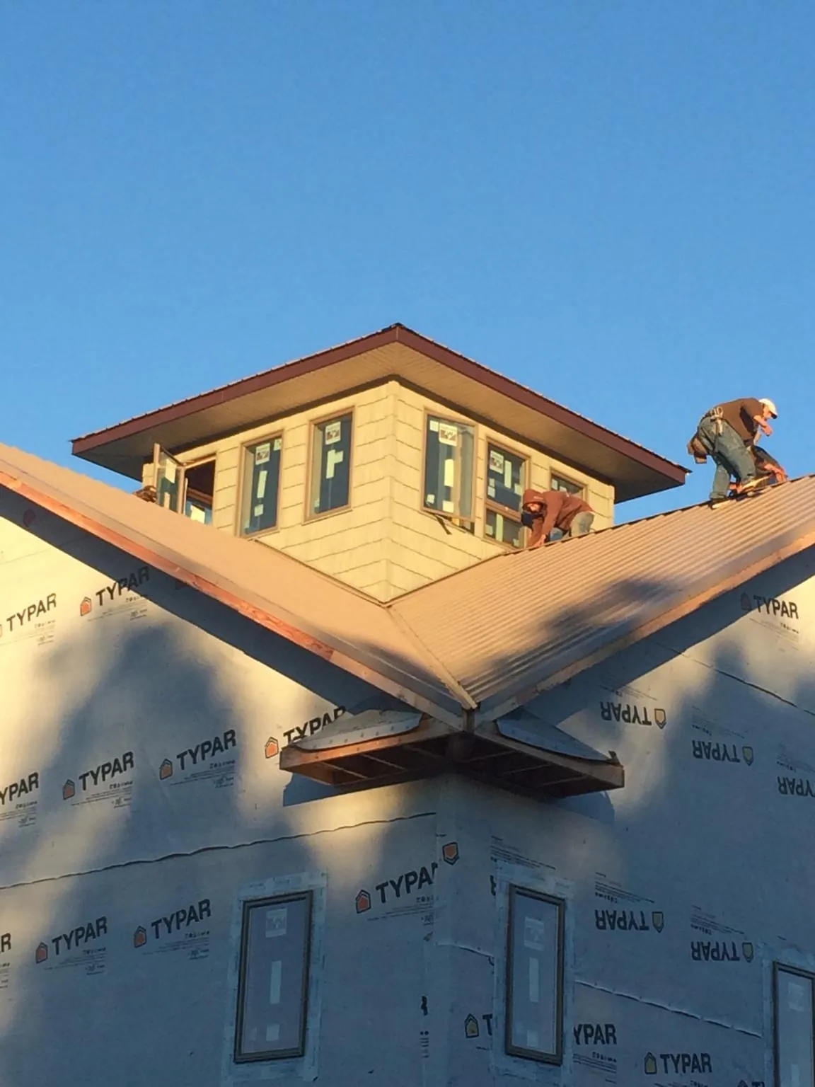 Roofers working around a rooftop cupola on a new metal roof at sunset — Roof Waterproofing in Callender by Roofing Brothers